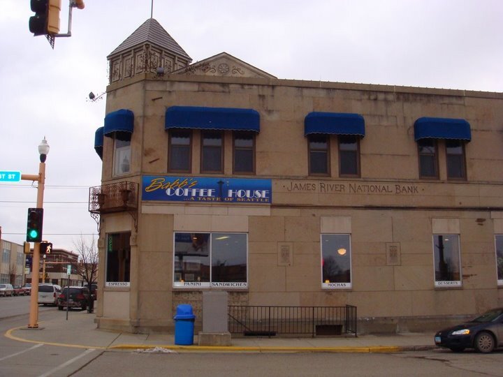 A view of a corner store an older style building along with white banners alongside the building.