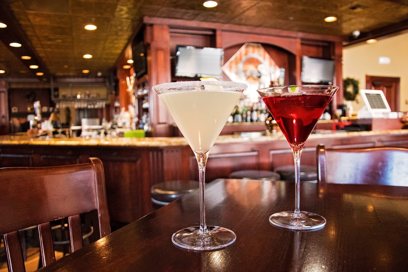 A view of a dimly lit decorated bar depicting two martini glasses.
