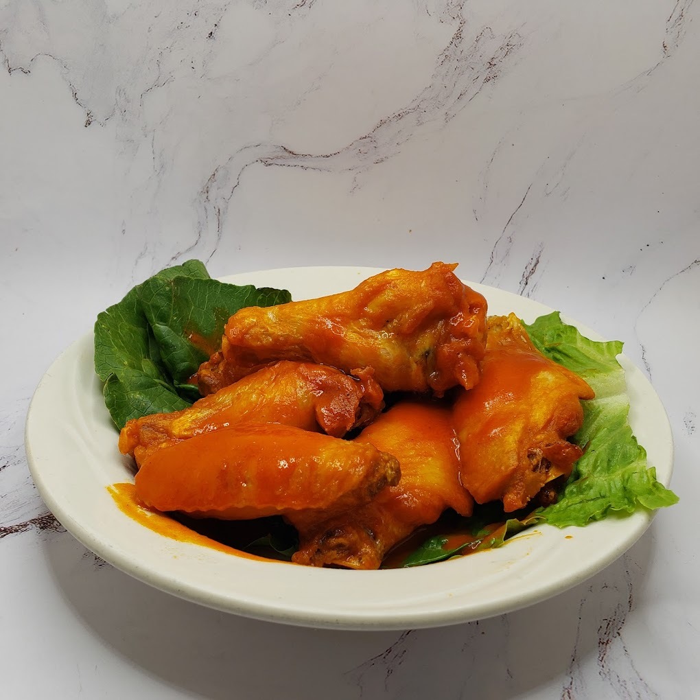 A white plate plated with lettuce and four wings with mild sauce.