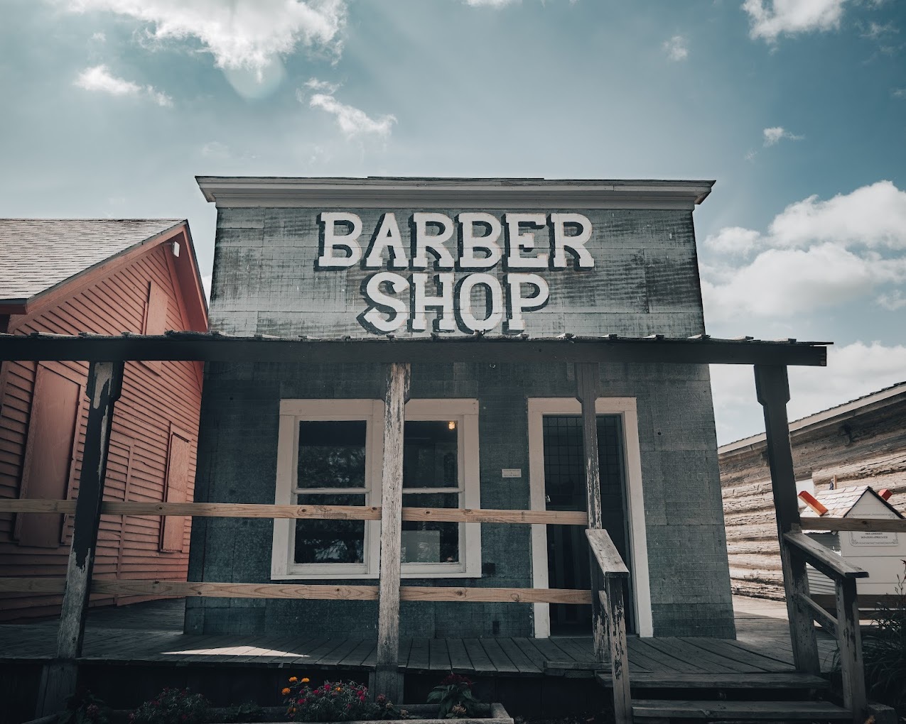 An outdoor view of a wild west building with large white lettering on the top of the building reading "Barber Shop"