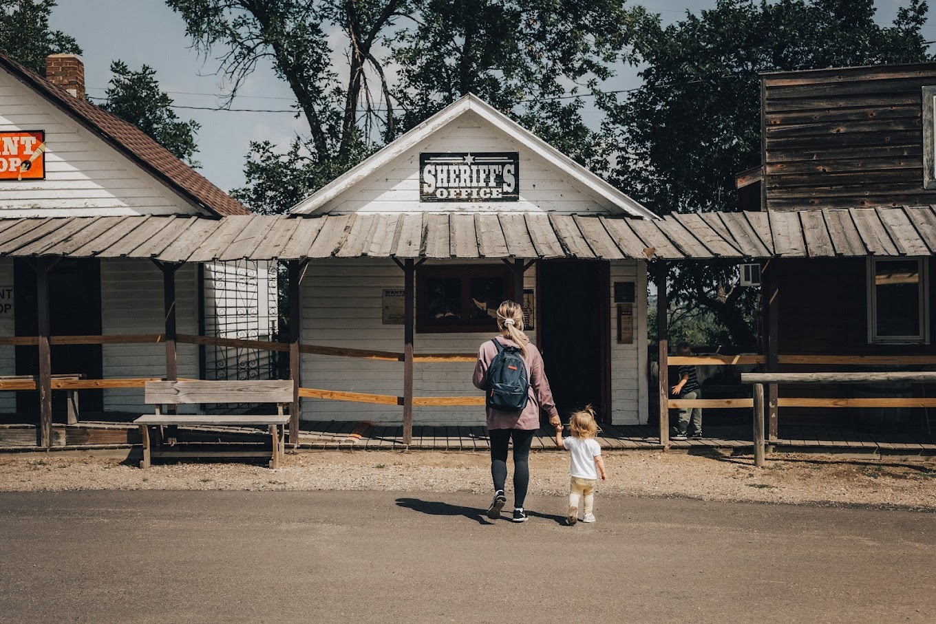 A view of a row of old time houses made to look like an old west town, a mother and child are making their way up to the historical sheriffs office.