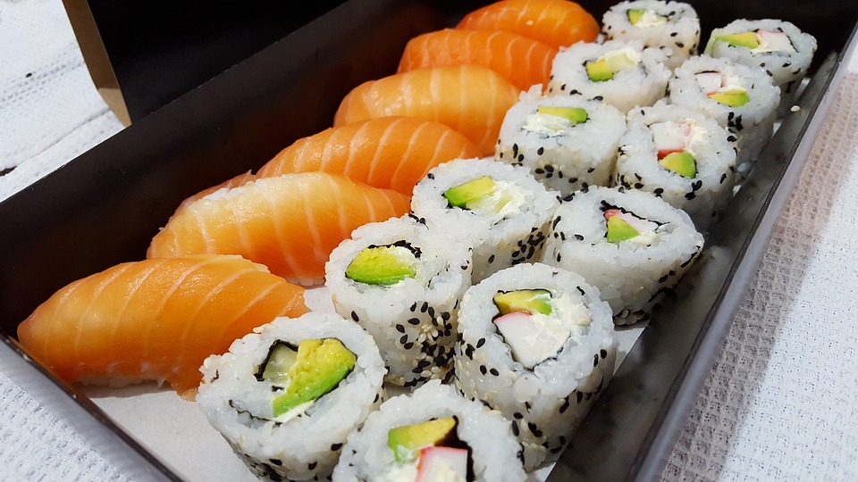 A black plate consisting of rows of sushi, such as rolls with cucumbers and fish rolls.
