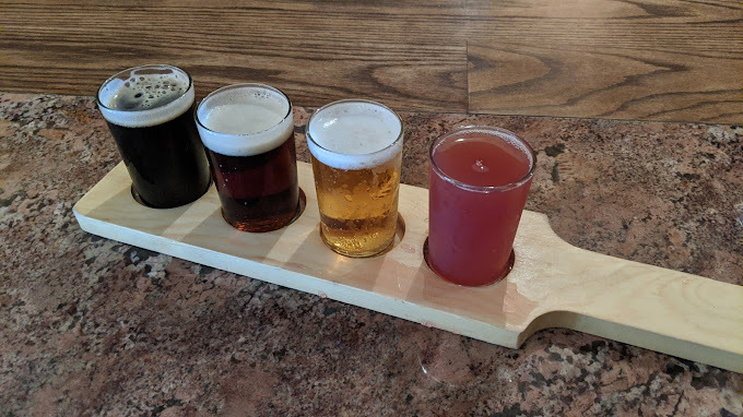 Four alcoholic drinks set in a wooden board.