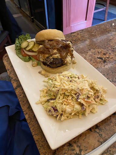 Burger and salad with ranch on a white rectangular plate, set on the edge of a table.