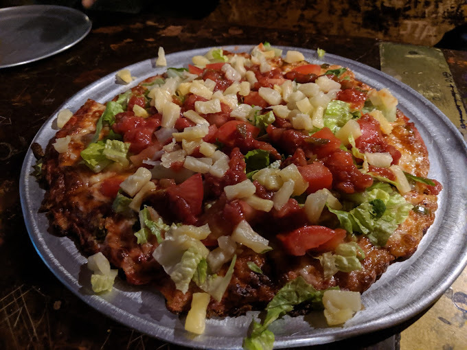 Close view of a pizza topped with numerous veggies on a metal plate.