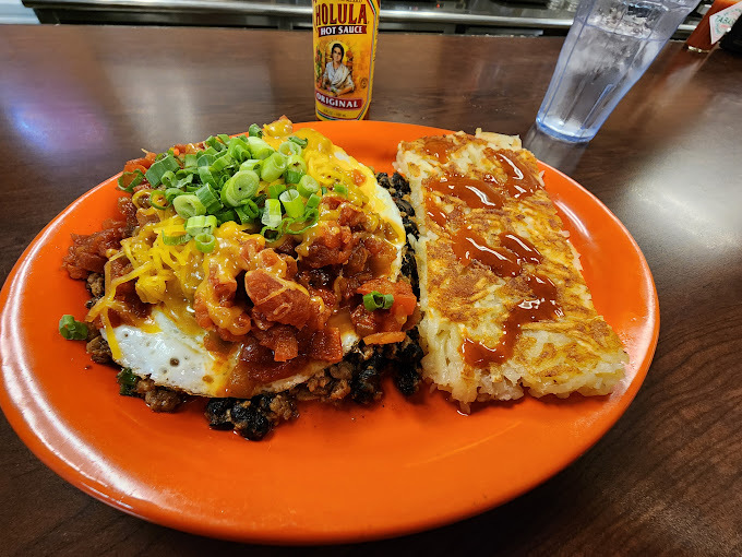Egg and hashbrown dish on an orange ceramic plate.