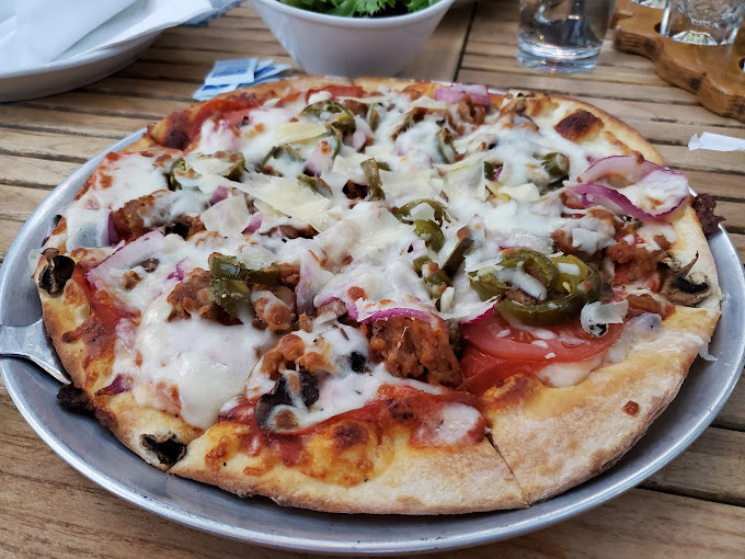 Fluffy pizza with greens and white cheese on a metal plate.