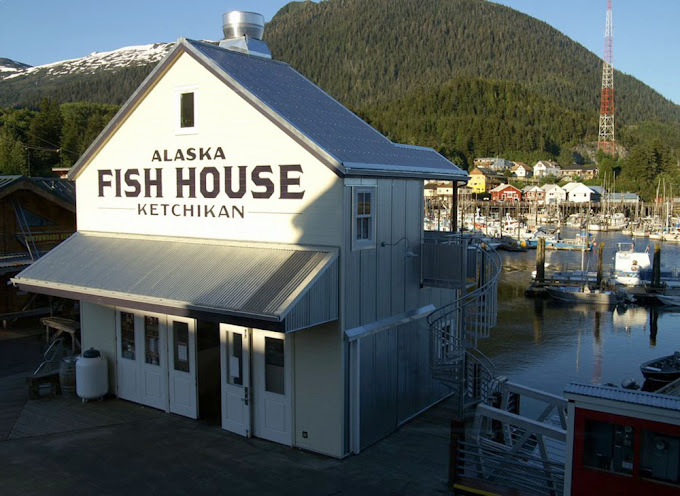Overhead view of a white building next to a body of water. Sign on building states "Alaska Fish House Ketchikan."