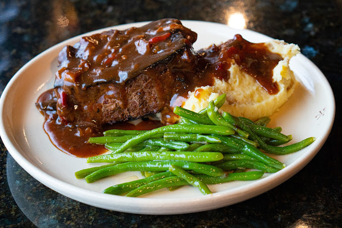 Steak, potatoes, and beans on a white plate.