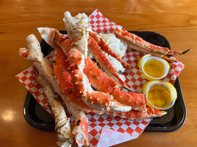 Seafood legs and butter on a red and white checkered paper on a black tray.