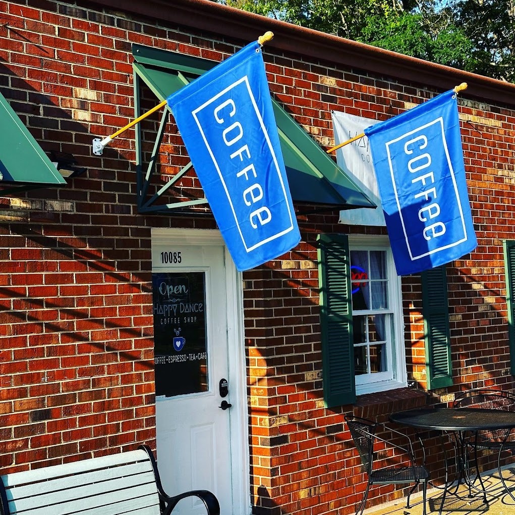 A red brick building with an white door and light blue flags reading "Coffee"