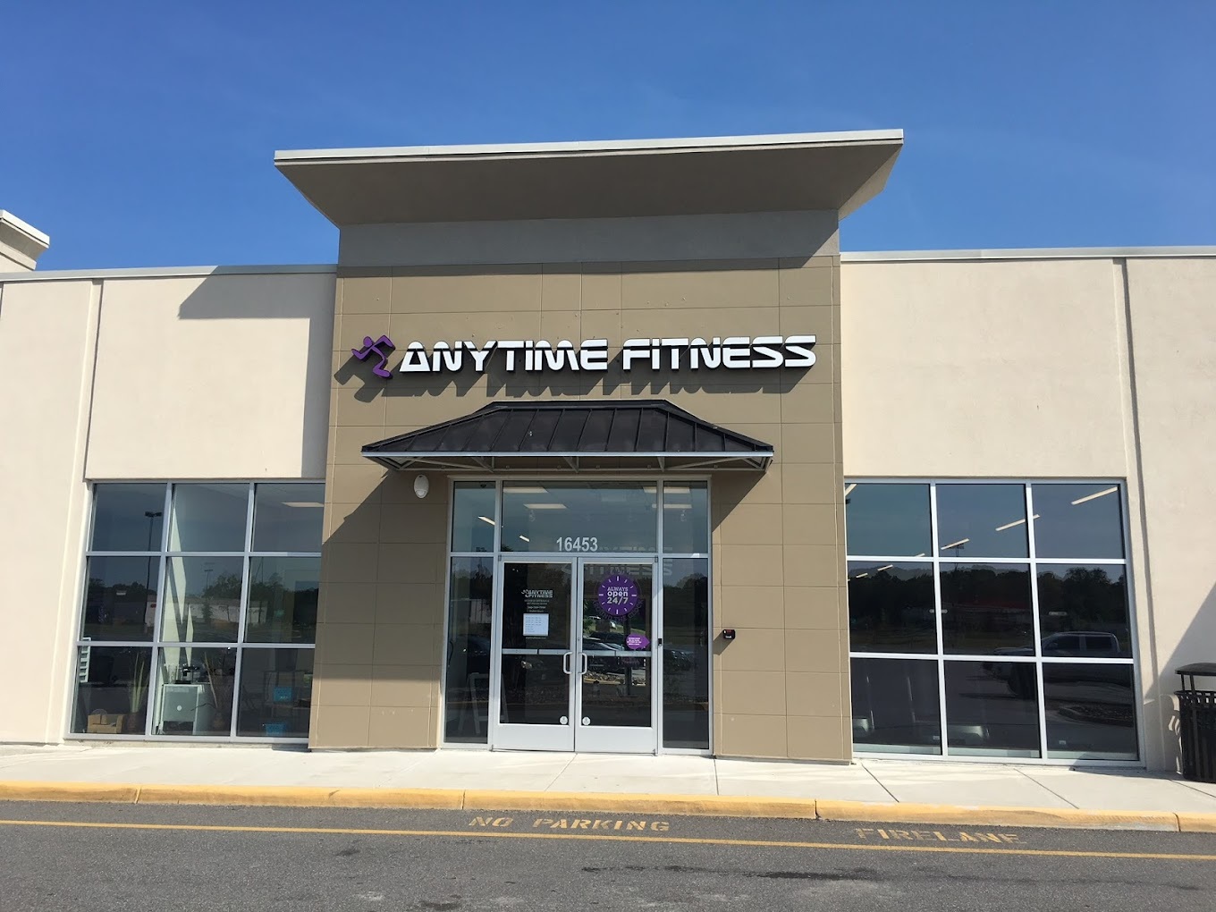 An outside view of an Anytime Fitness with white lettering and purple logo above the entrance.