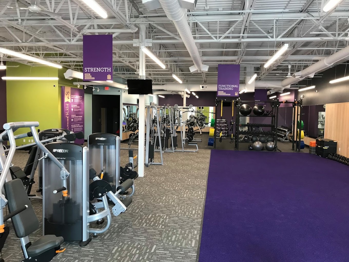 An inside view of an Anytime Fitness gym, purple carpeting and accenting surrounds the room, including purple flags around the ceiling of the gym.