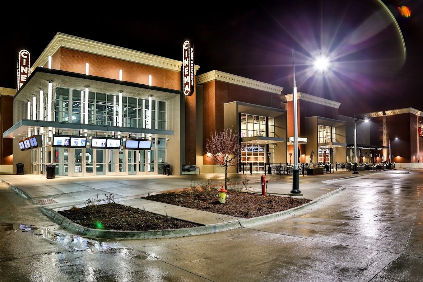 An outside view of a modern styled theatre at night, with many large windows.