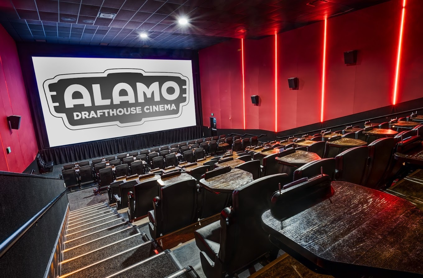 A theatre with luxury seats and moody lighting against the red walls.
