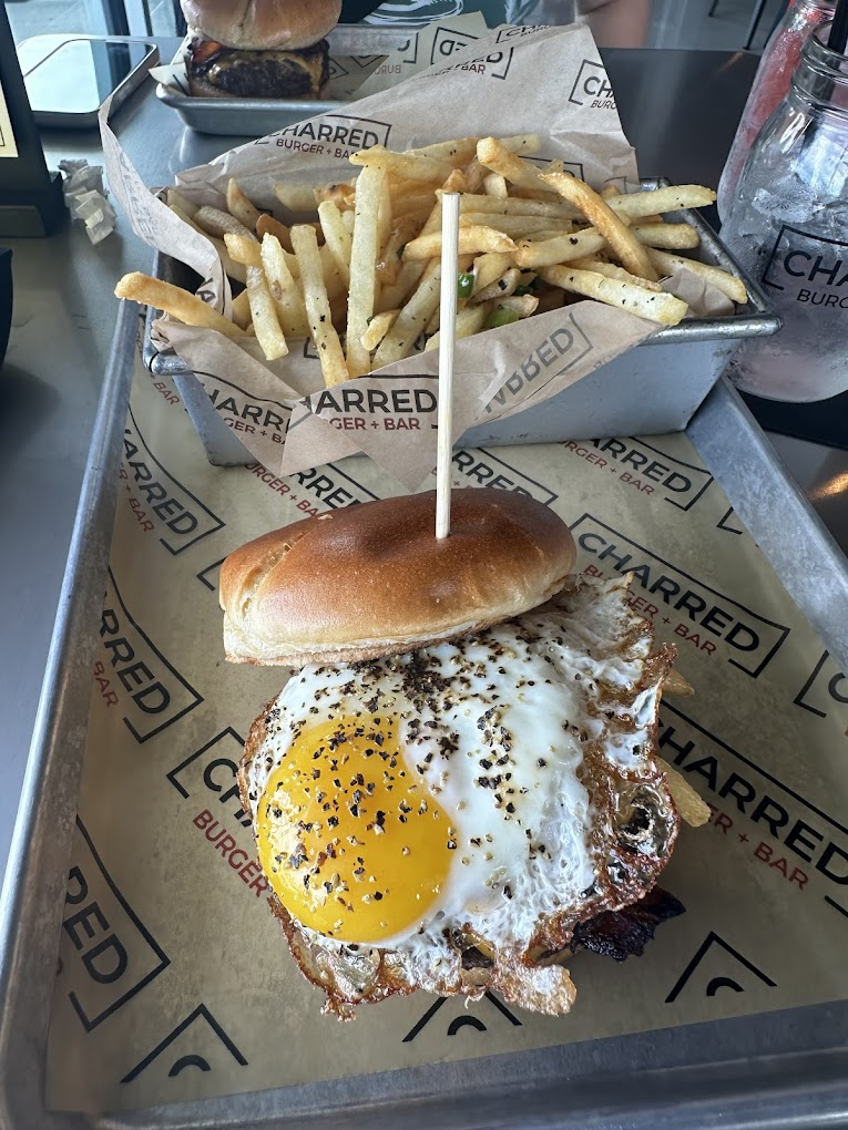A serving tray with a burger with an egg, and a side of classic cut French fries.
