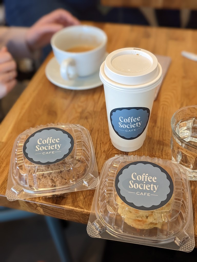 A view of two coffees and two baked goods inside of a plastic to-go container.