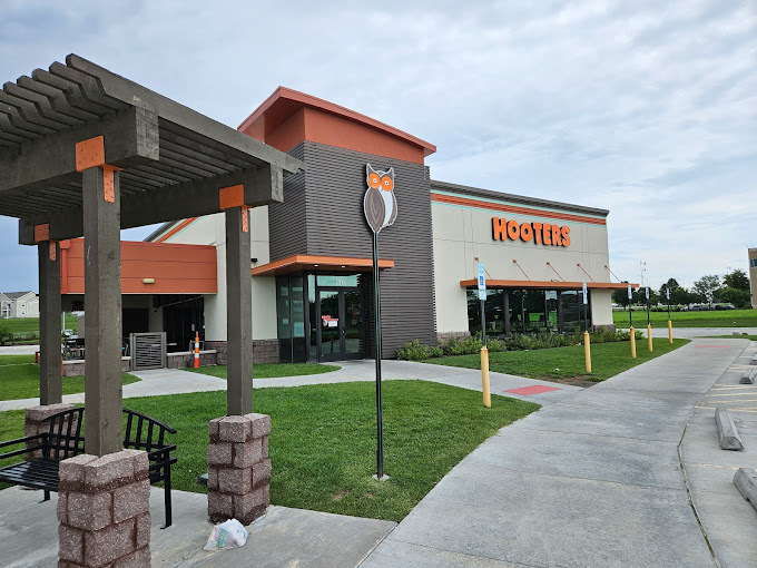 An outside view of a modern styled restaurant with orange accenting and orange lettering on the side of the building.