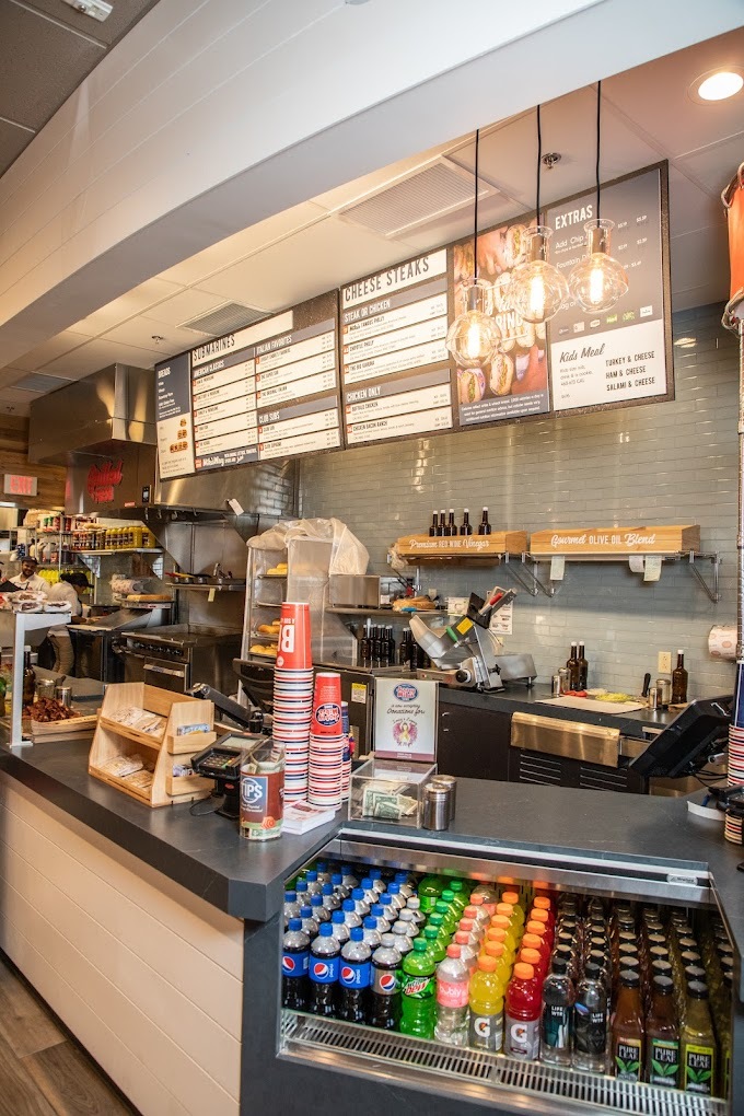 A view of sandwich shop counter, with a view of a grab and go cooler.