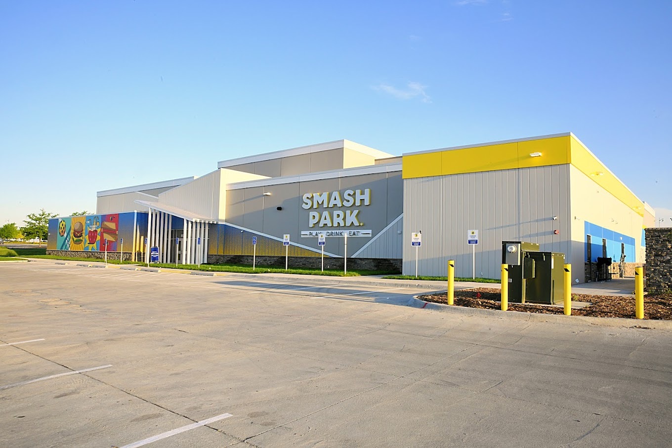 An outside view of an entertainment venue, a modern styled building grey with yellow accenting.