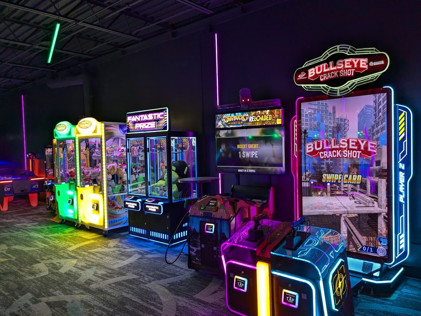 A view of a dark room full of brightly lit arcade games.