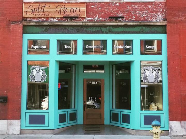 An view of an café entrance, an red brick building with teal lined windows and door.