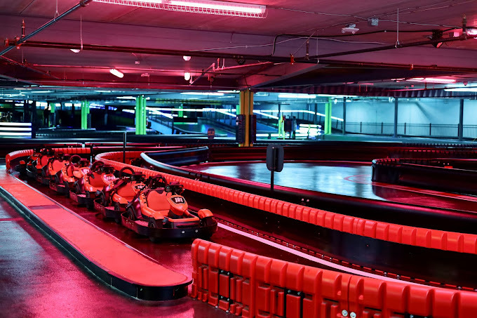 Red lit go kart road entrance. Numerous karts are lined up on the side.