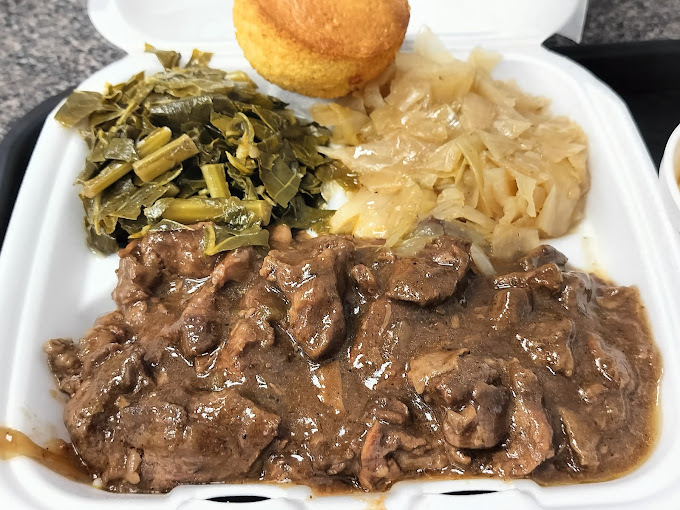 Brown meat. green beans, and a muffin in a white Styrofoam takeout container.