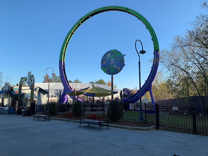 Green circular roller coaster with a fence surrounding it.