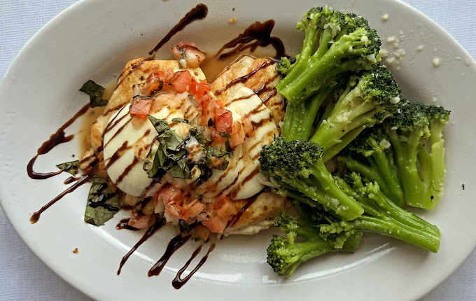 Dish of chicken and broccoli drizzled with a brown sauce, all on a white plate.