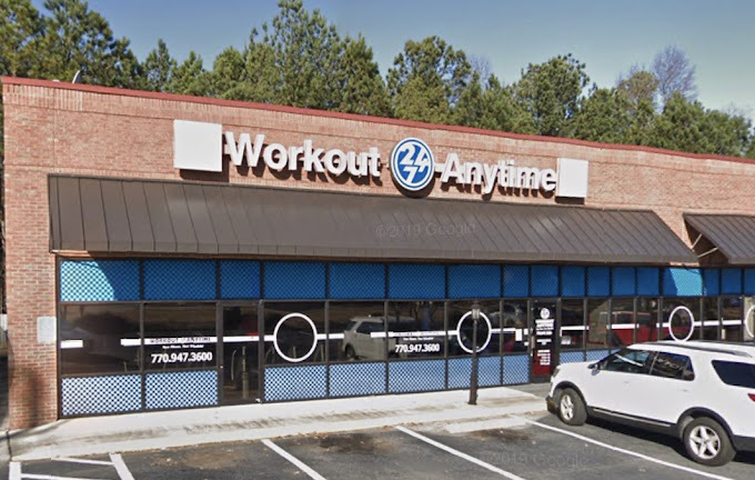 Flat red brick building with a strip of brown sunshades. The windows and doors have blue and white checkered paper on the glass.