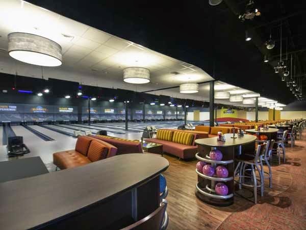 Bowling alley with red couches and additional bar stool seating behind them.