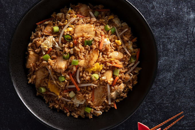 Rice and chicken dish in a black bowl.