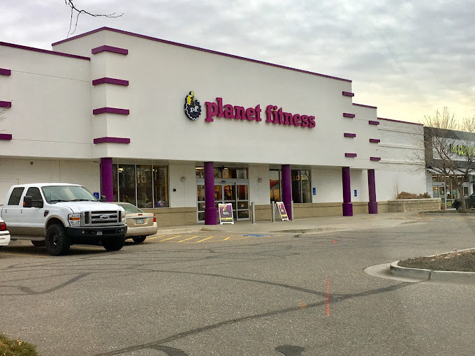 White building with purple accents ad columns. Sign above the door reads "Planet Fitness."