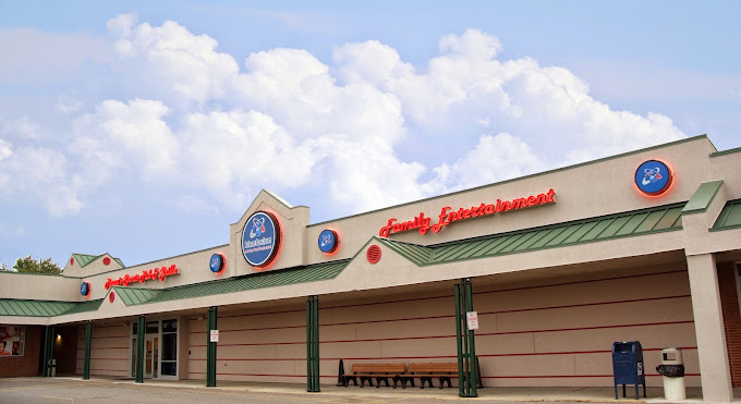 Beige building with triangular points and green roofing and columns. There are blue circular logos with orange backlighting. The text across the building in orange cursive says "family entertainment."