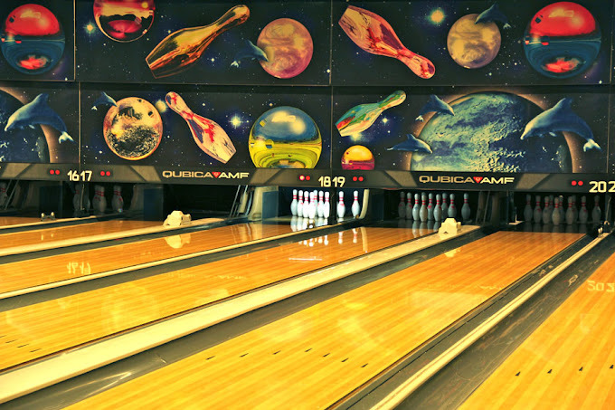 Bowling alley lanes with bowling and outer space themed wall decoration.