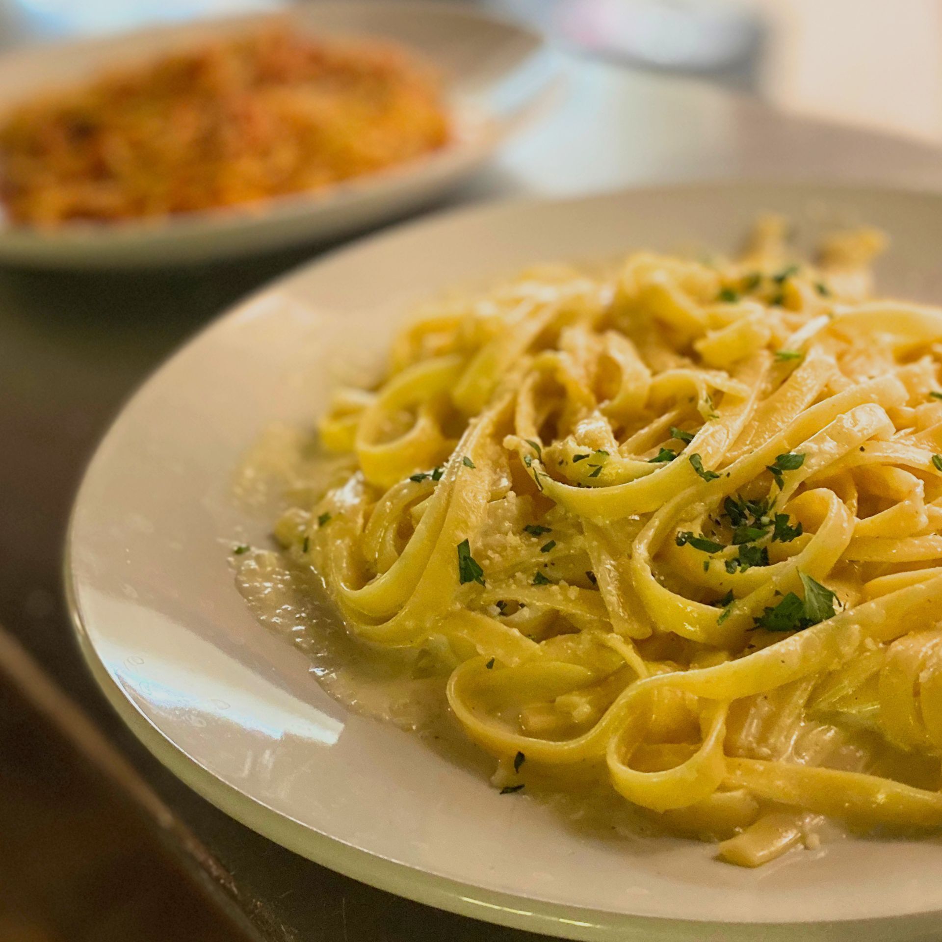 Close view of a plate of pasta with sauce and seasoning on a white circular plate.
