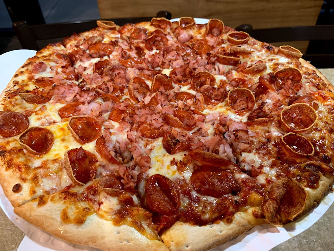 Close view of a fluffy ham and pepperoni sliced pizza.