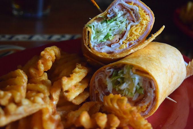 Sandwich wraps made with lettuce, meat, and cheese, as well as waffle fries.