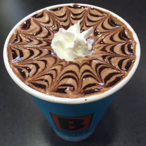 A view of a coffee with whipped cream and a kaleidoscope latte art on top.