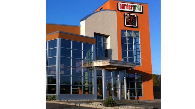 An outside view of a building with a modern style, orange accenting and lots of windows incorporated into the boxy shaped design.