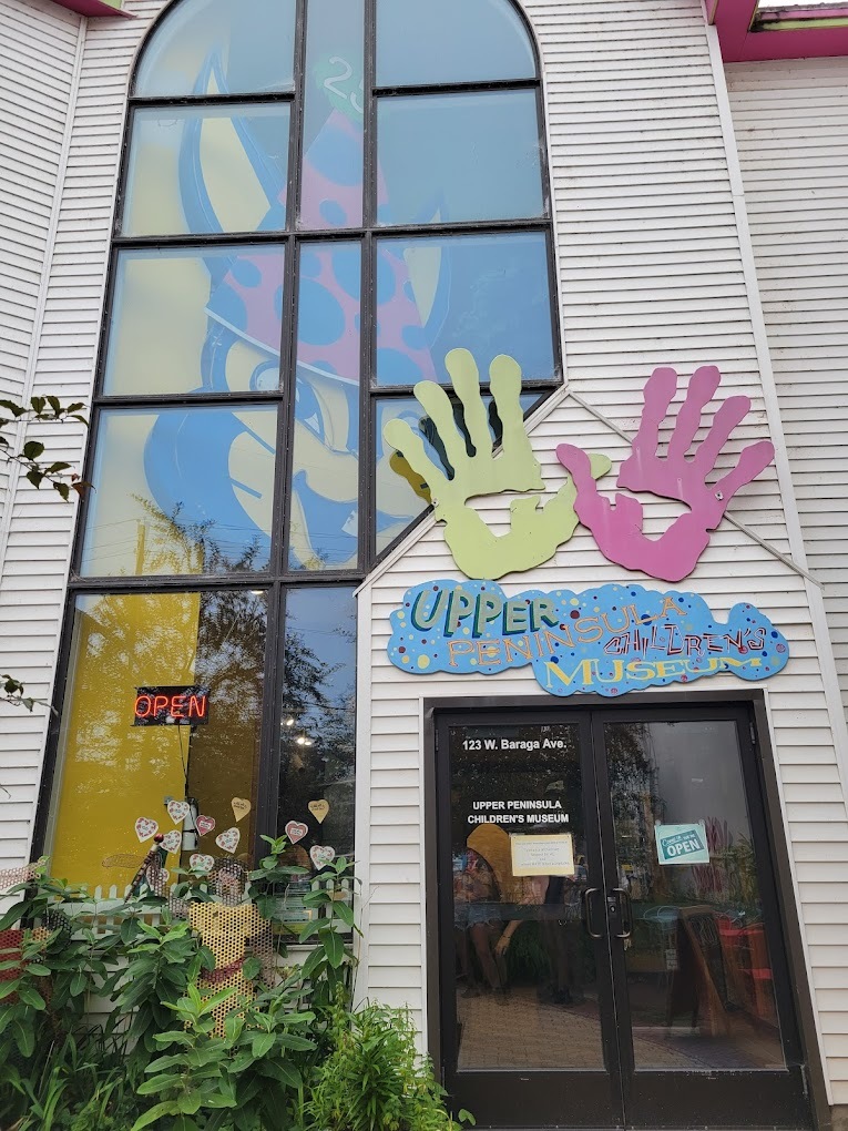 A view of a large white brick building with many windows and a colorful sign depicting handprints.