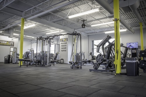 A view of gym work out equipment in a room with yellow pillars in the middle of the room.