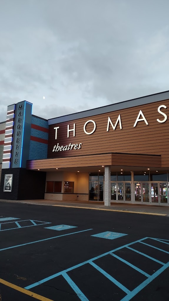 An outside view of a large modern brick building with blue accenting and white lettering on the side that reads "Thomas"