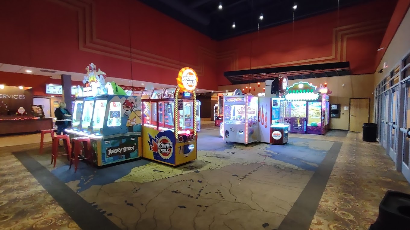 An inside view of a large arcade room full of illuminated games.