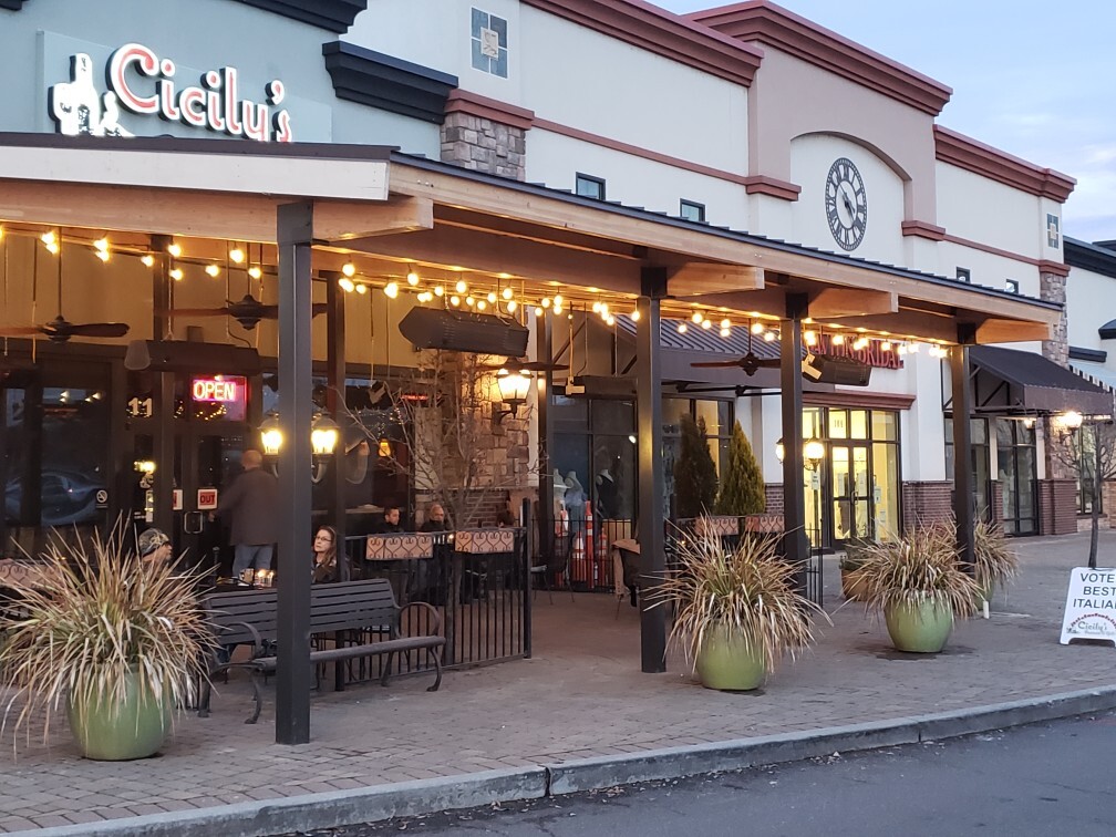 An front entrance to a restaurant with outdoor string lights and seating.