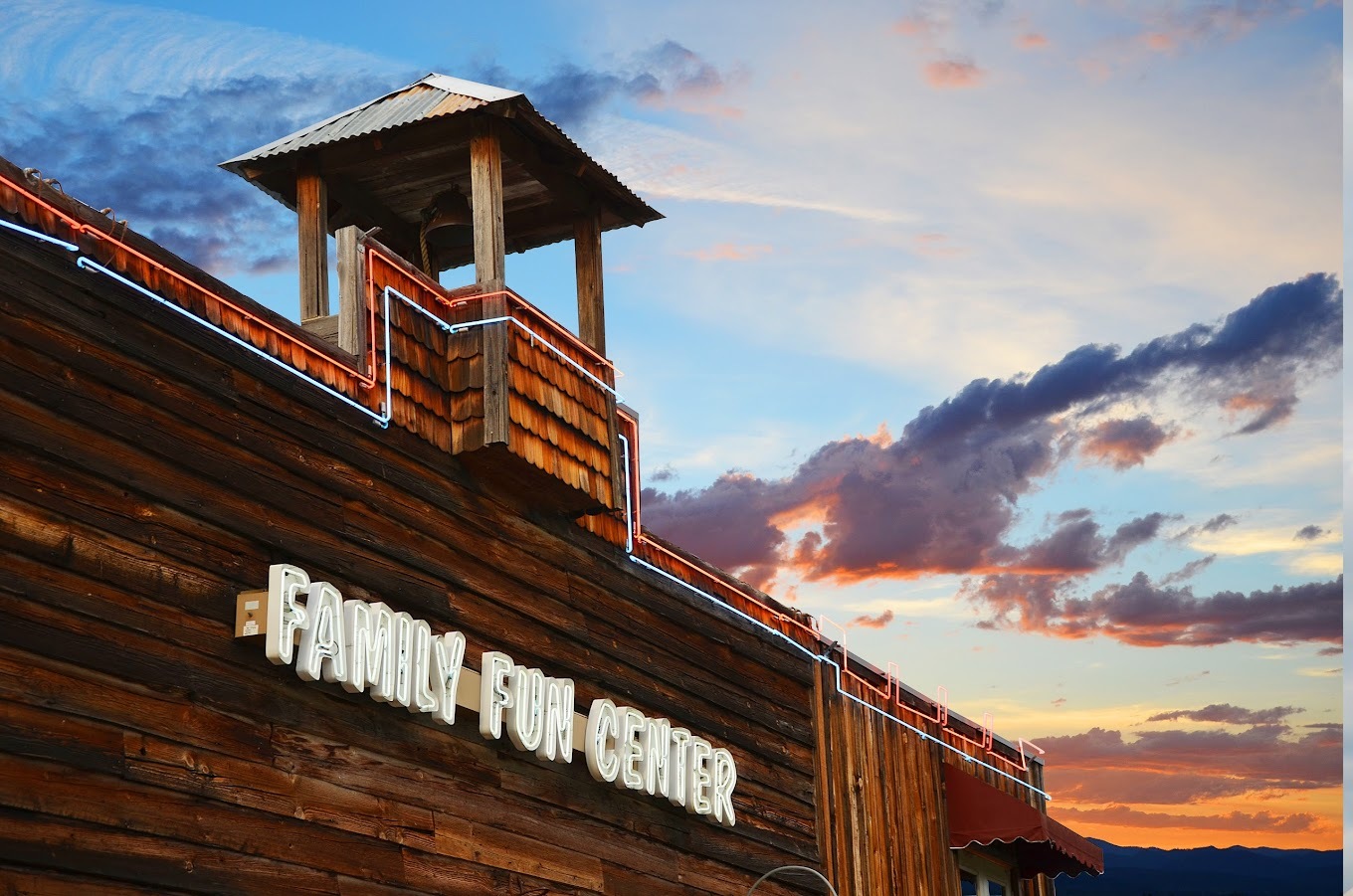 Landscape photo of a large wooden building with the lettering "Family Fun Center" in white neon lights