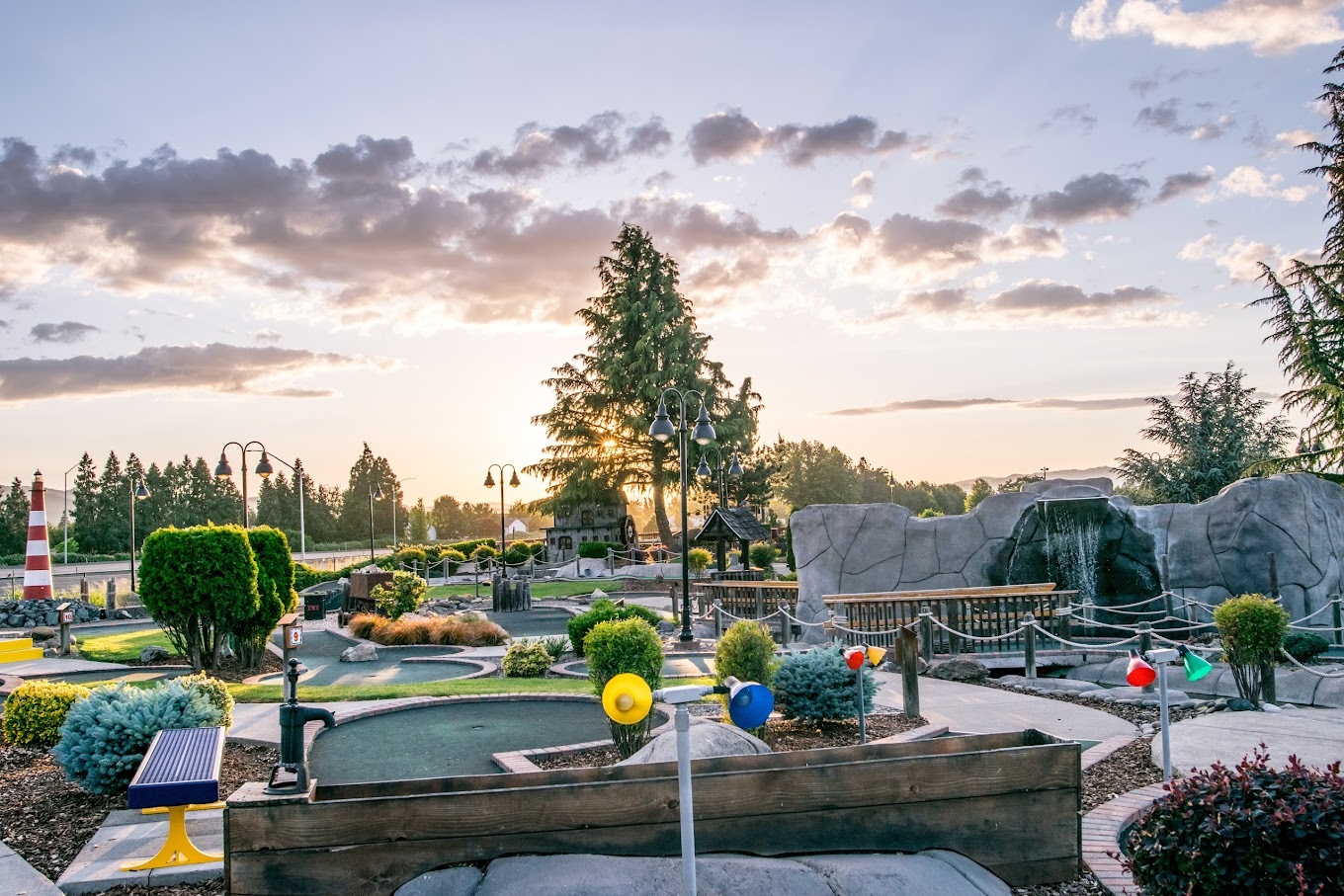 Landscape photo depicting mini golf park and a sunset.