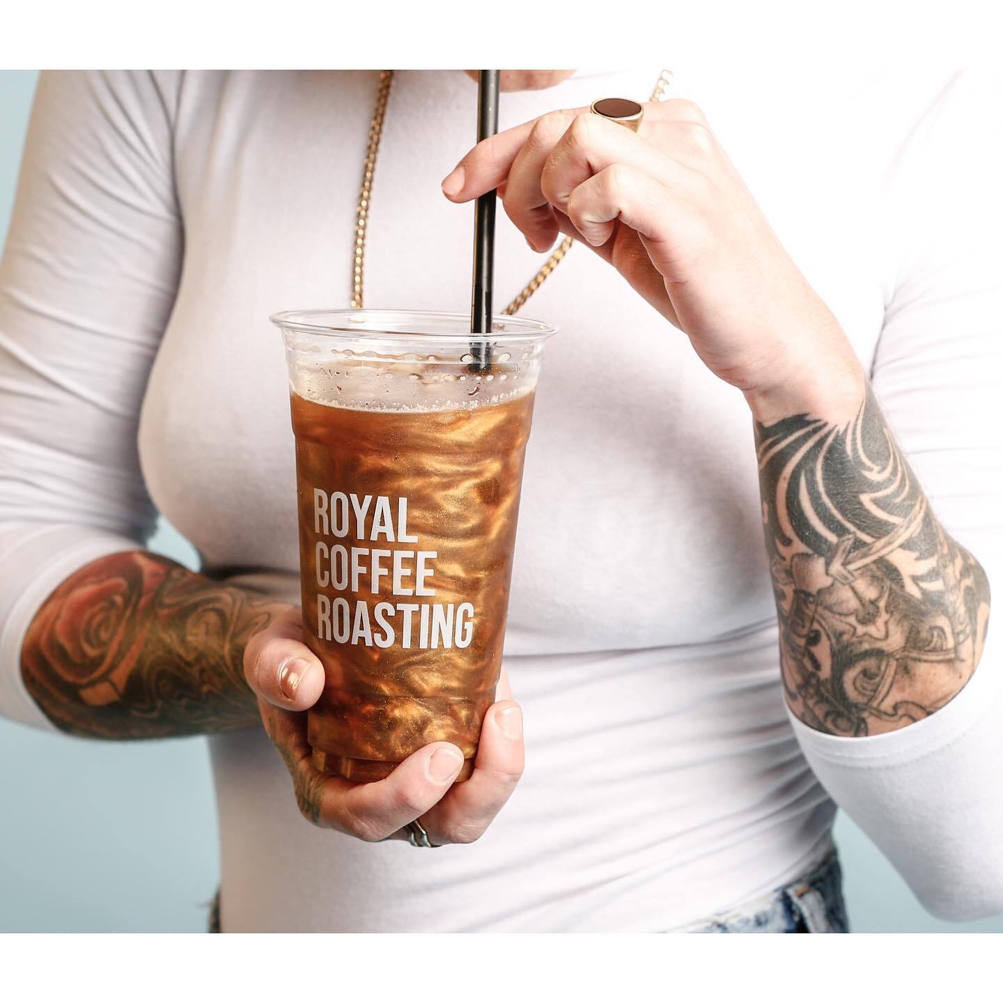 An view of a woman holding and mixing together an large iced coffee.