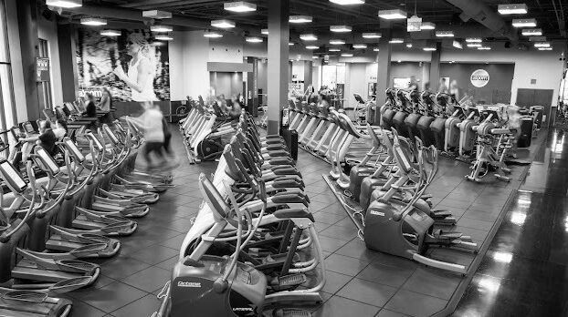 Greyscale interior view of workout machines.